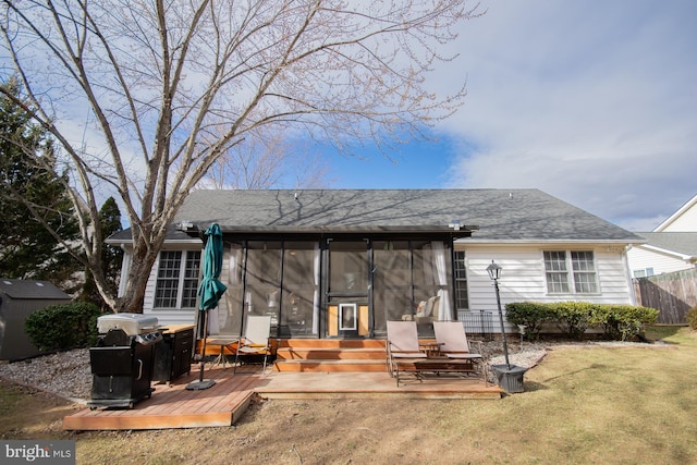 back of property with roof with shingles, a yard, a sunroom, fence, and a deck