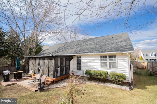 rear view of property featuring a yard, a patio area, fence, and a sunroom