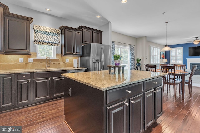 kitchen with a center island, dark wood-type flooring, a sink, plenty of natural light, and stainless steel fridge with ice dispenser