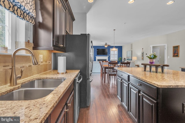 kitchen with dark wood-style flooring, a fireplace, decorative backsplash, a sink, and dishwasher