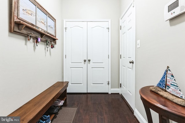 mudroom featuring dark wood-type flooring and baseboards