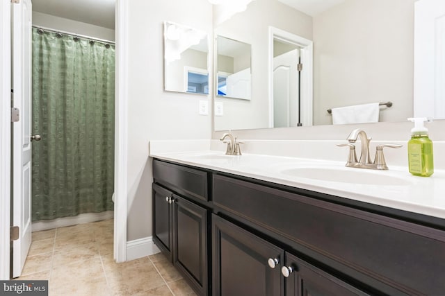 bathroom with double vanity, tile patterned flooring, a sink, and baseboards