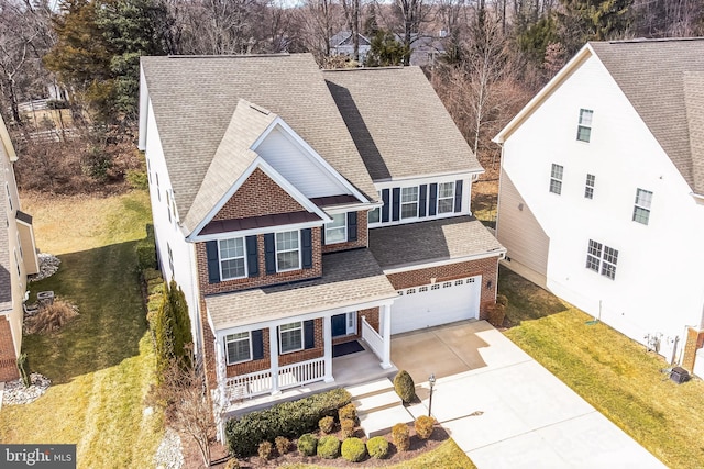 view of front facade with a shingled roof, concrete driveway, an attached garage, a porch, and brick siding