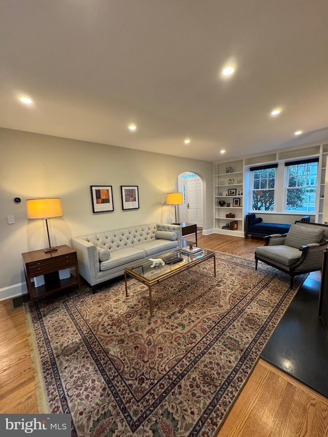 living area with arched walkways, baseboards, wood finished floors, and recessed lighting