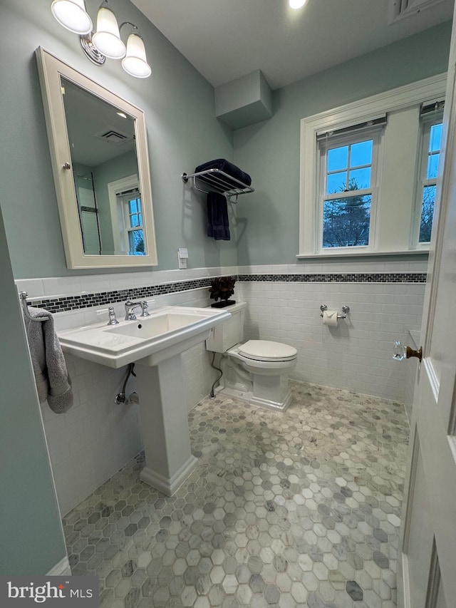 bathroom featuring visible vents, wainscoting, toilet, tile patterned flooring, and tile walls