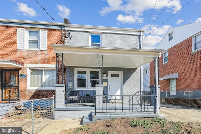 townhome / multi-family property with fence, covered porch, and brick siding