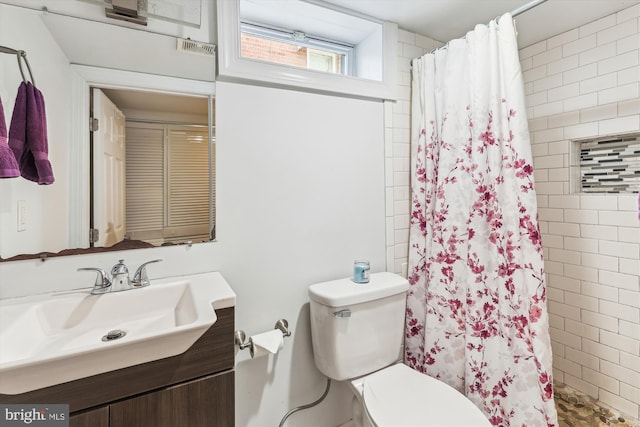 full bath with a tile shower, toilet, and vanity