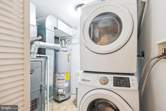 clothes washing area featuring laundry area, water heater, and stacked washing maching and dryer