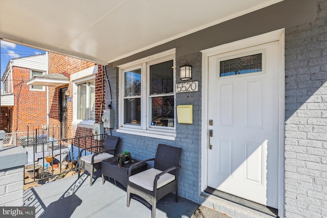 view of exterior entry featuring covered porch and brick siding