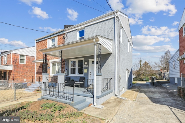 multi unit property with a porch, fence, and brick siding