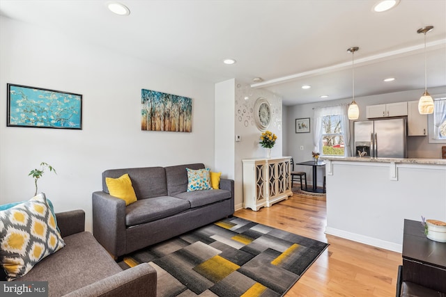 living room with recessed lighting, baseboards, and light wood-style floors