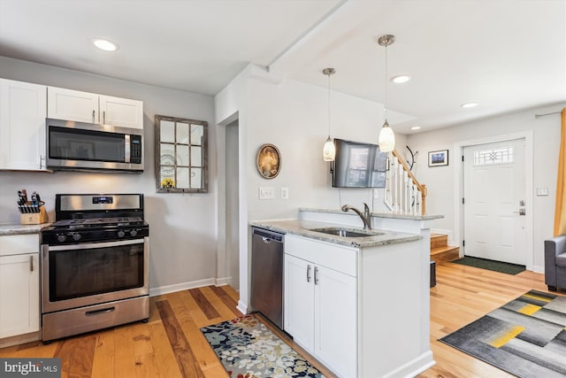 kitchen featuring a sink, a peninsula, white cabinets, and stainless steel appliances