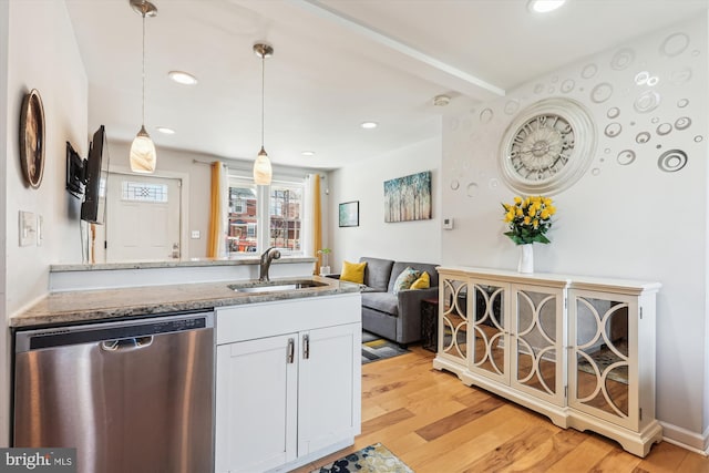 kitchen featuring pendant lighting, light wood-type flooring, light stone counters, stainless steel dishwasher, and a sink