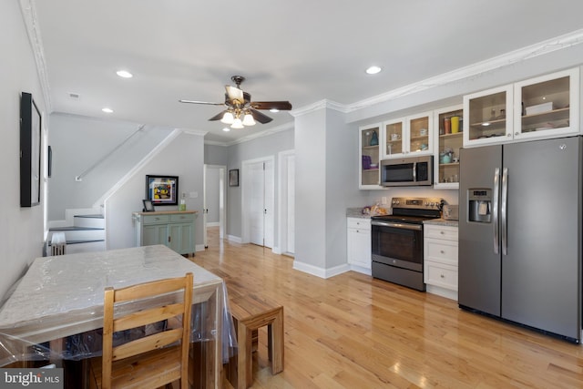 kitchen featuring ornamental molding, white cabinetry, stainless steel appliances, light wood finished floors, and glass insert cabinets