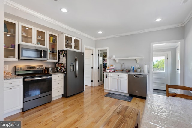 kitchen featuring white cabinetry, light wood-style flooring, ornamental molding, and stainless steel appliances