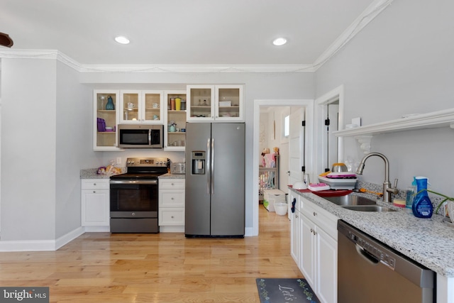 kitchen featuring open shelves, a sink, appliances with stainless steel finishes, crown molding, and light wood-type flooring