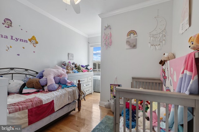 bedroom with crown molding, light wood-style flooring, and radiator heating unit