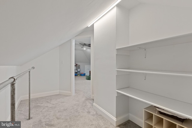 interior space featuring vaulted ceiling, a ceiling fan, baseboards, and carpet floors