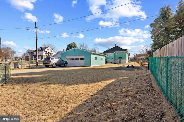 view of yard featuring an outdoor structure, a garage, and fence