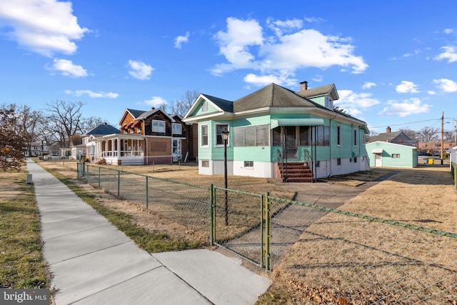 bungalow-style home with a fenced front yard, entry steps, a chimney, and a gate