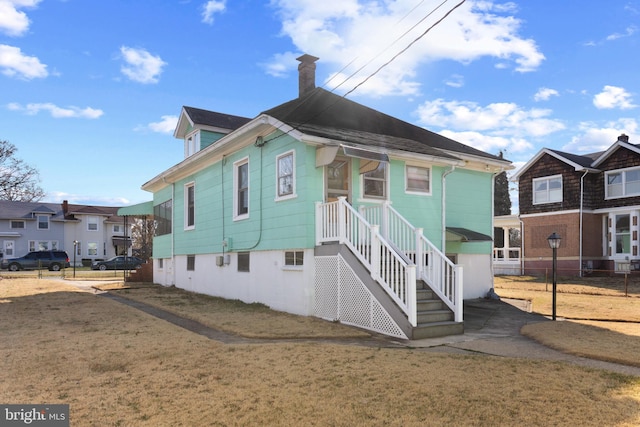 view of front facade with a residential view, a front lawn, a chimney, and fence