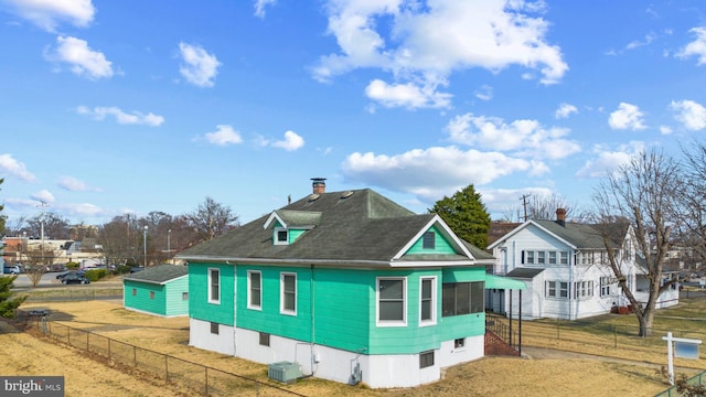 view of property exterior featuring central air condition unit, a lawn, roof with shingles, fence private yard, and a chimney