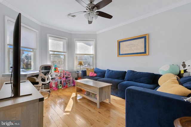 living room with light wood finished floors, plenty of natural light, ceiling fan, and ornamental molding