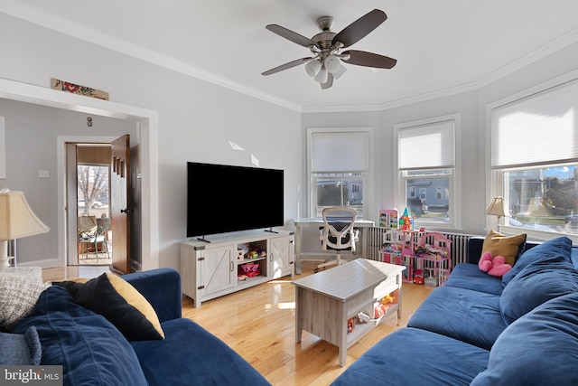 living room featuring ceiling fan, plenty of natural light, wood finished floors, and crown molding