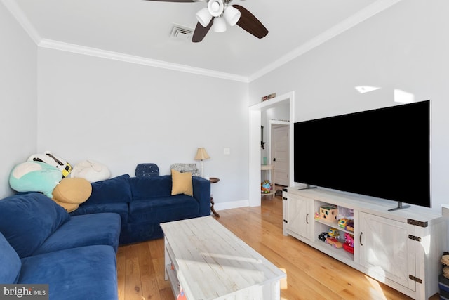 living room with light wood finished floors, visible vents, a ceiling fan, and ornamental molding