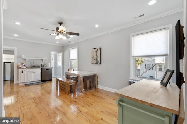 dining space featuring a ceiling fan, baseboards, light wood finished floors, and ornamental molding