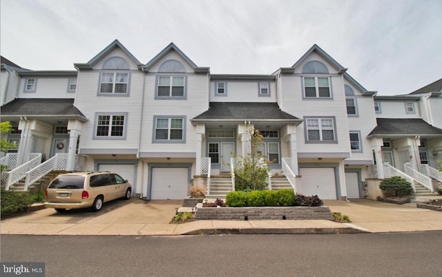 view of property with a garage, driveway, and stairway