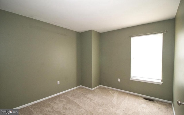 spare room featuring baseboards, visible vents, and carpet flooring