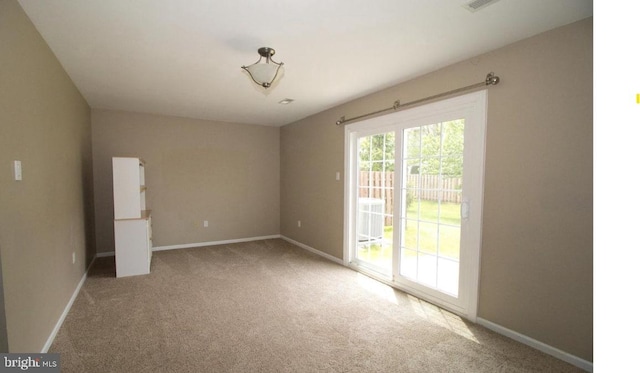 carpeted empty room featuring baseboards