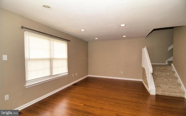 empty room with stairs, recessed lighting, wood finished floors, and baseboards