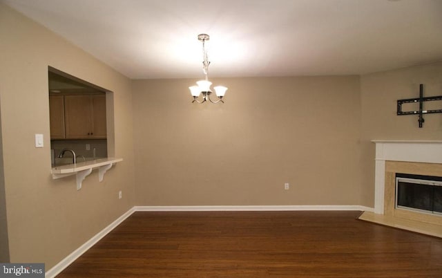 unfurnished living room featuring dark wood-style floors, a fireplace with flush hearth, baseboards, and a notable chandelier