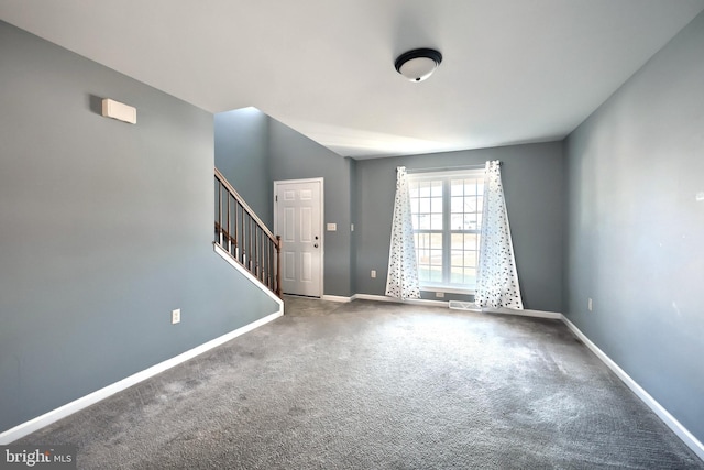 carpeted empty room featuring baseboards and stairway