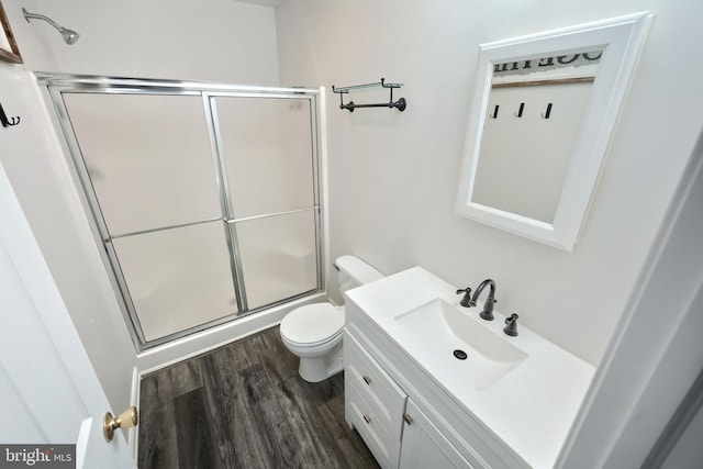 full bathroom featuring toilet, vanity, wood finished floors, and a shower with shower door