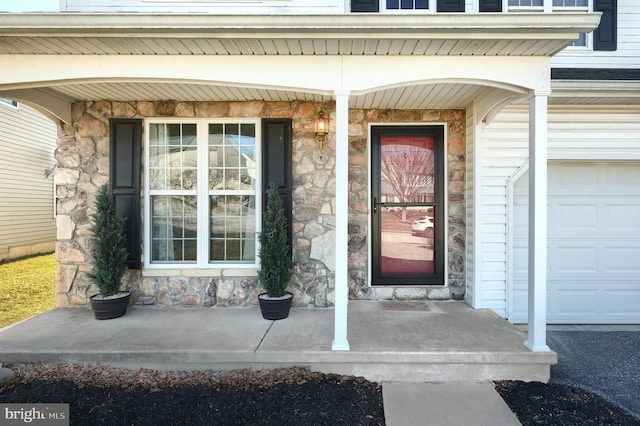 property entrance featuring a garage, covered porch, and stone siding