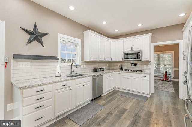 kitchen with a sink, white cabinetry, tasteful backsplash, and stainless steel appliances