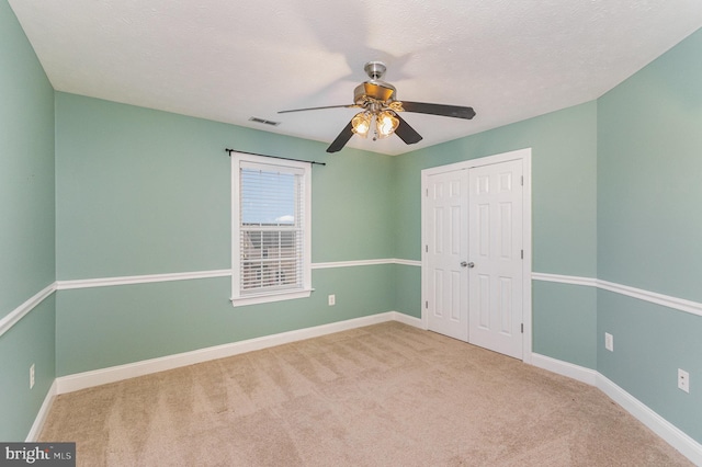 unfurnished bedroom with ceiling fan, visible vents, baseboards, a closet, and carpet
