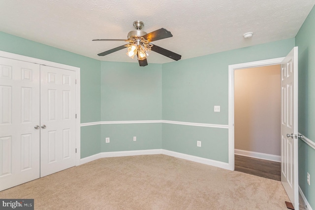 unfurnished bedroom featuring a closet, carpet flooring, baseboards, and a ceiling fan