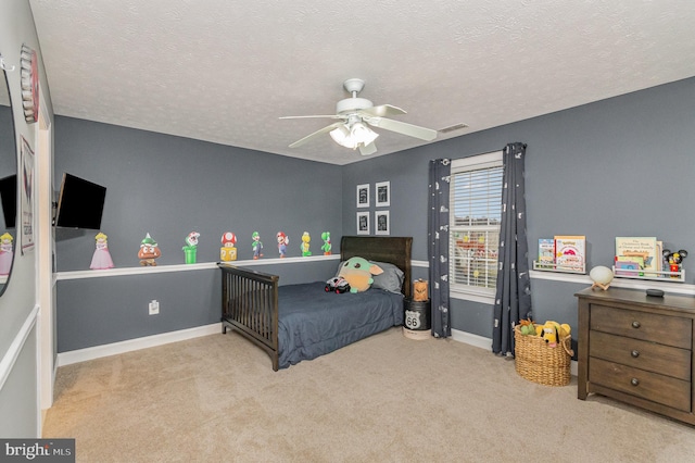 carpeted bedroom featuring visible vents, a ceiling fan, baseboards, and a textured ceiling
