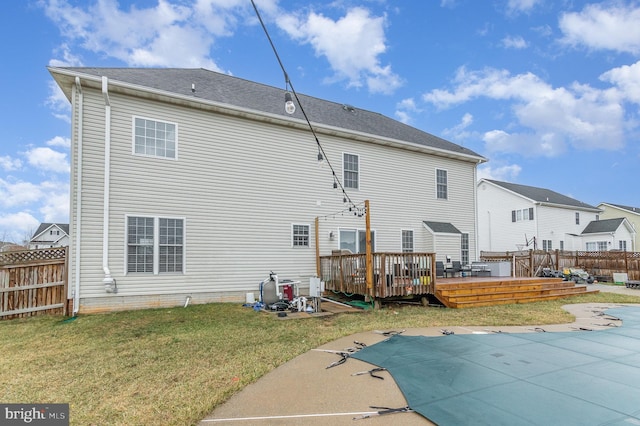 back of house featuring a fenced backyard, a fenced in pool, a yard, and a deck