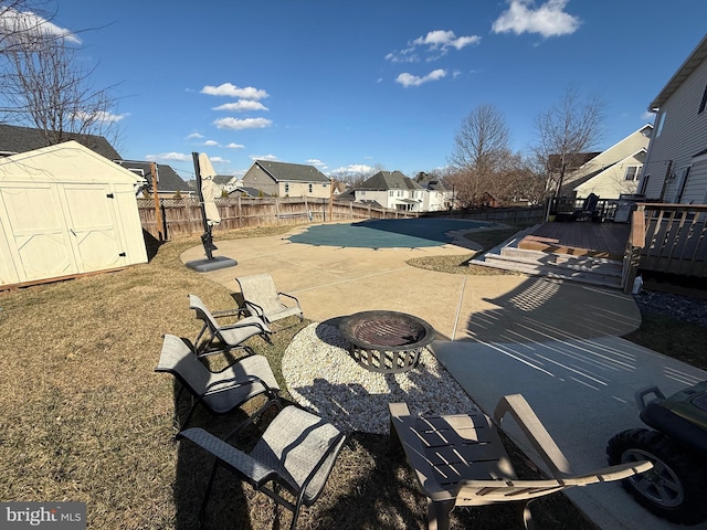 view of patio with a fenced backyard, a residential view, an outbuilding, a deck, and a shed