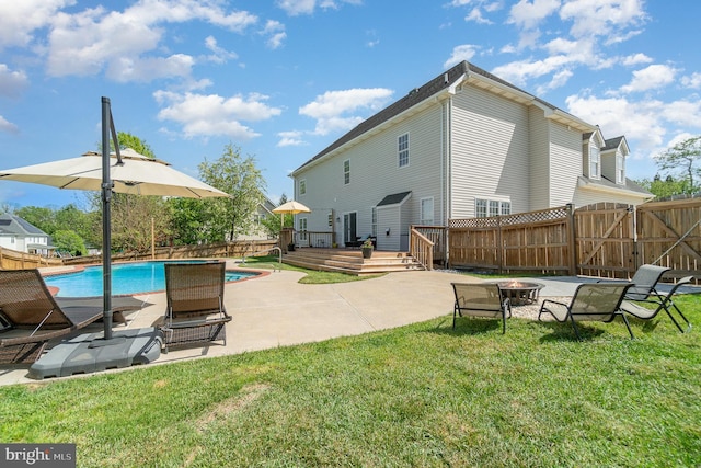 rear view of property featuring a lawn, a fenced backyard, an outdoor fire pit, and a deck
