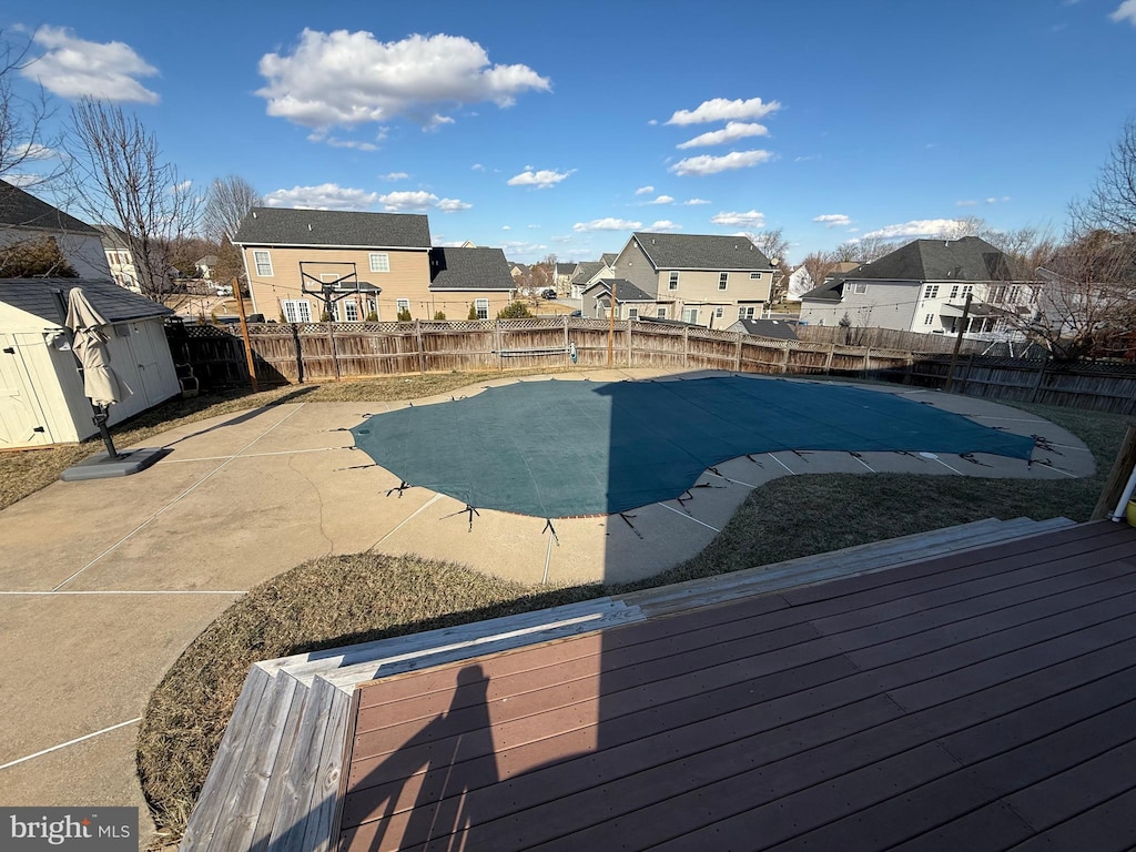 view of pool with a patio, a fenced backyard, a residential view, a fenced in pool, and a shed