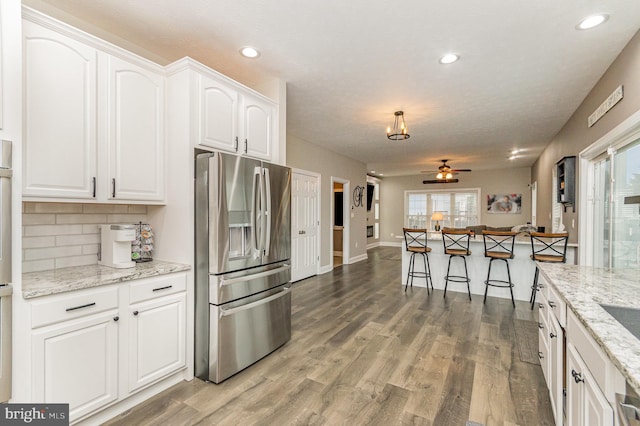 kitchen featuring white cabinets, stainless steel fridge, tasteful backsplash, recessed lighting, and light wood-type flooring