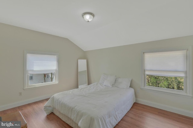 bedroom featuring baseboards, wood finished floors, and vaulted ceiling