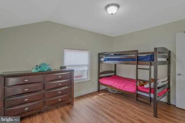 bedroom featuring baseboards, wood finished floors, and vaulted ceiling