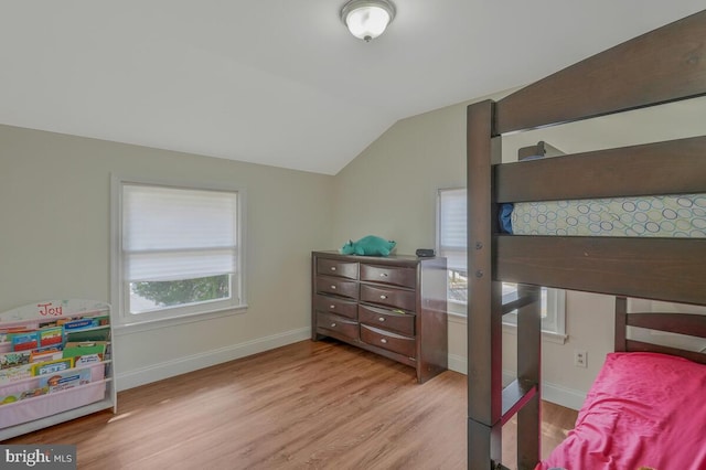 bedroom with wood finished floors, baseboards, and vaulted ceiling